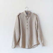 Oatmeal half button-up long sleeve linen shirt with dark brown buttons, collar and shoulder straps.