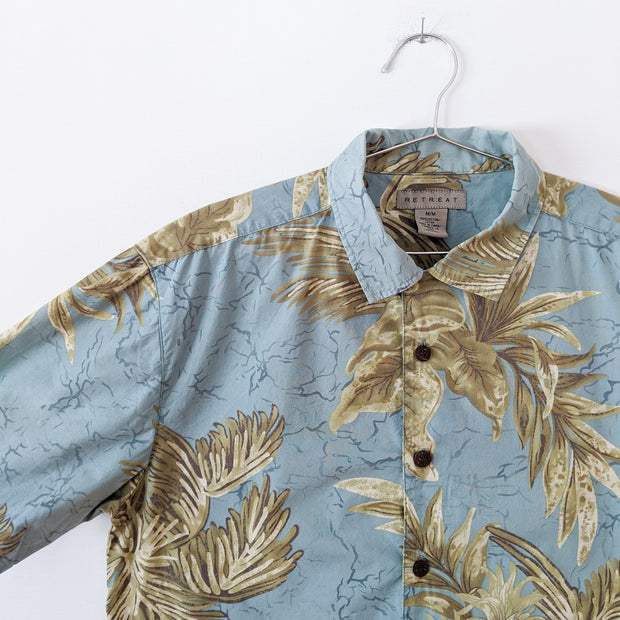 Short Sleeve Button-up Hawaiian Shirt. Light Teal Tropical Print Yellow and Green Pineapples. Brown Wood Buttons. Close up.