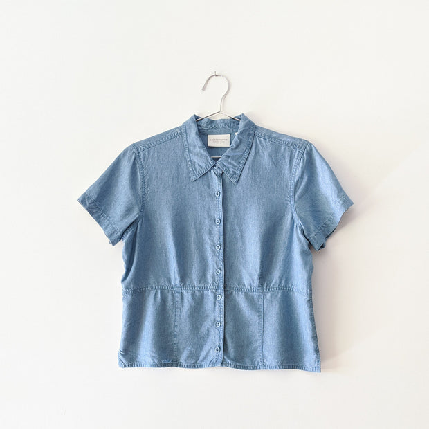 Light Indigo Blue button-up petite t-shirt with collar, visible waistline like a subtle peplum, darts for fitting and covered buttons.