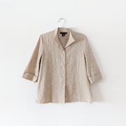 Linen and Rayon button-up three-quarter sleeve shirt in Oatmeal (beige) with all-over embroidery. It has a mandarin/fold-down collar with v-neck, cuffed sleeves with slits, large glossy buttons, and 4" side slits. Laura Scott Petite. Secondhand from Fold and Fray in Canada.