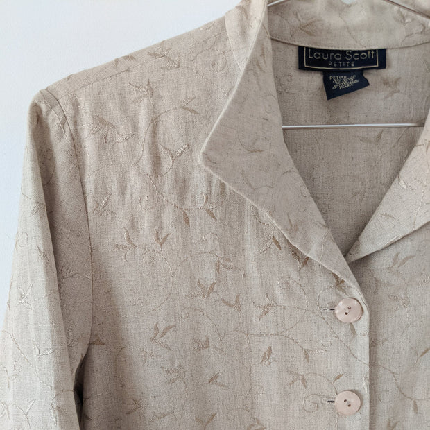 Closeup of collar on button-up three-quarter sleeve shirt in Oatmeal (beige) with all-over embroidery. Mandarin/fold-down collar, with large glossy buttons. Vine embroidery. Laura Scott Petite. Secondhand from Fold and Fray in Canada.