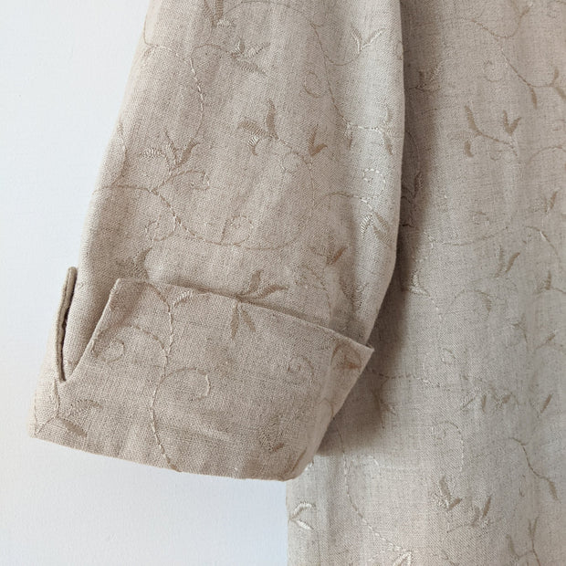 Close-up of sleeve on button-up three-quarter sleeve shirt in Oatmeal (beige) with all-over embroidery. The sleeve cuff has small slit. Laura Scott Petite. Secondhand from Fold and Fray in Canada.