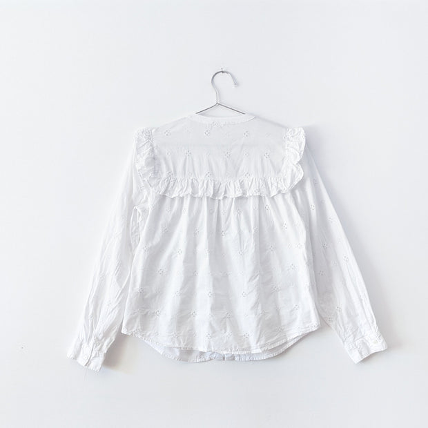 Back of White cotton eyelet blouse, long sleeve, with square ruffle across the shoulder blade area.