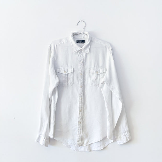 White linen long sleeve button-up shirt with two chest pockets that have button flaps.