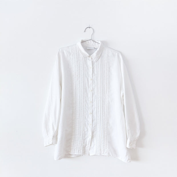 White linen long sleeve button-up shirt with vertical pleats, six inch side slits, and white ladder lace trim down the center on the front. Liz Claiborne Lizsport. Secondhand from Fold and Fray.