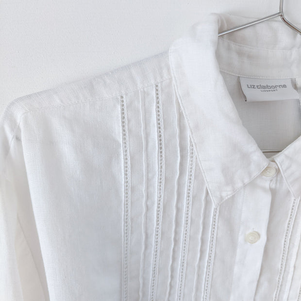 Close-up on a white linen long sleeve button-up shirt. Shows white lace ladder trim and pleating on the front.  Liz Claiborne Lizsport. Secondhand from Fold and Fray.