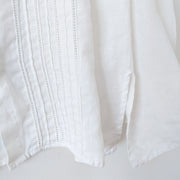 Detail of the pleating and side slit on the front of a white linen long sleeve button-up shirt.  Liz Claiborne Lizsport. Secondhand from Fold and Fray.