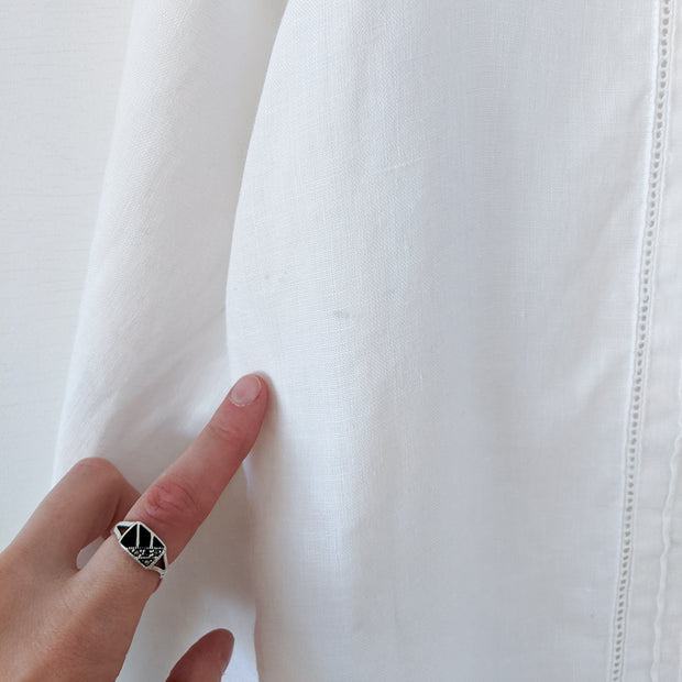 Detail of a tiny small mark on the front of a white linen long sleeve button-up shirt. Secondhand Liz Claiborne Lizsport Large, from Fold and Fray.