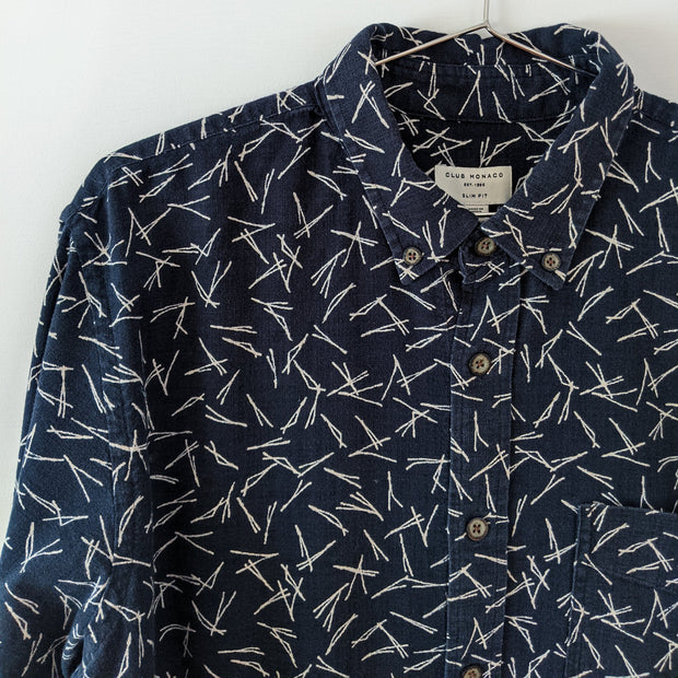 Closeup of button-down collar with dark buttons on a Dark Navy and White button-down shirt. Print looks like small pine needles. Club Monaco, Slim Fit. Seconhand from Fold and Fray.