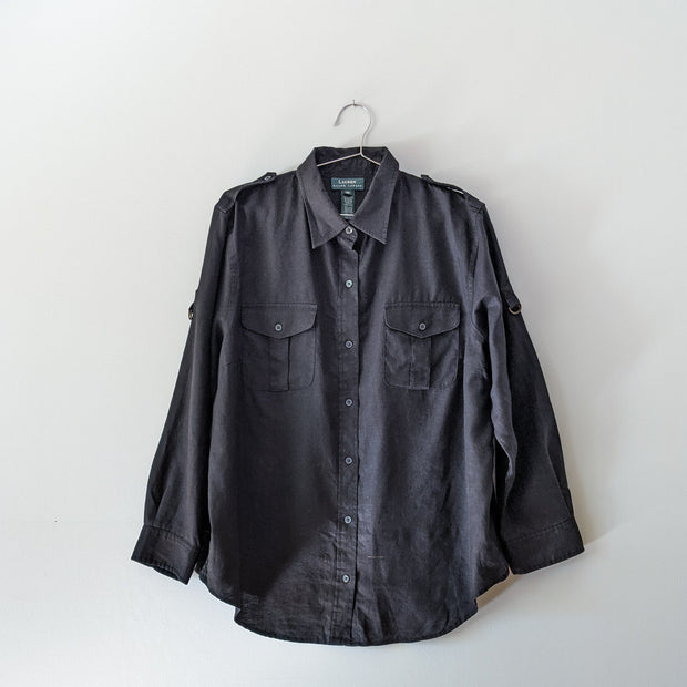 Black linen button-up long sleeve shirt with collar, shoulder straps, and roll-up sleeves that loop. There is a dye mark imperfection on the front by the bottom.