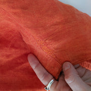 Close up of Woven Repair Detail on Back Seam, Linen Fabric on Button-up Long Sleeve Shirt, Bright Rosy Orange.