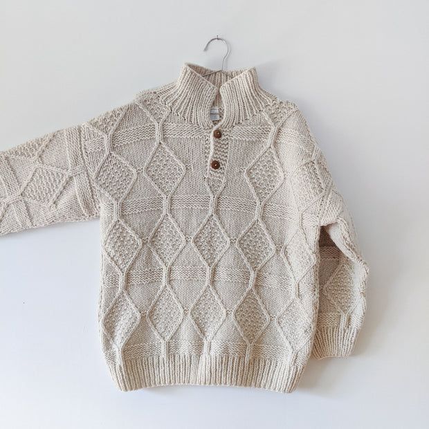 Vintage wool sweater in Light Ecru, chunk knit, polo-style collar with wooden buttons, arm extended showing wide sleeve width.