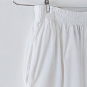 White cotton capri-length pants with wide straight leg. Close-up of textured cotton, elastic waistband and side slash pockets. Mexico Lindo Moda Artesanal en Manta. Secondhand from Fold and Fray.