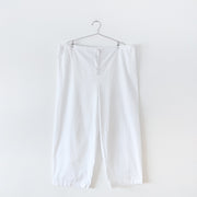 White cotton pyjama pants with straight leg and drawstring and elastic waist, with the waist fully extended to show full width. Secondhand gender and size inclusive clothing from Fold and Fray.