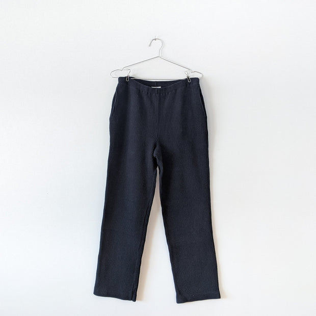 Black vintage vertical-ribbed stretch cotton-knit pants with straight leg, narrow elastic waistband and side slash pockets. Jones New York. Secondhand from Fold and Fray.