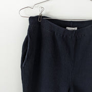 Close-up of vertical ribbed cotton fabric, elastic waistband and slash pocket, on Black vintage ribbed stretch cotton-knit pants. Jones New York. Secondhand from Fold and Fray.