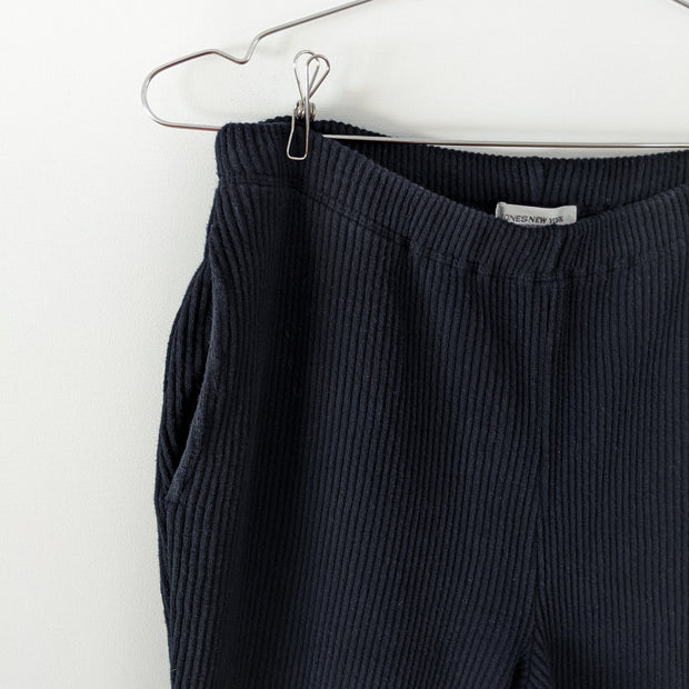Close-up of vertical ribbed cotton fabric, elastic waistband and slash pocket, on Black vintage ribbed stretch cotton-knit pants. Jones New York. Secondhand from Fold and Fray.