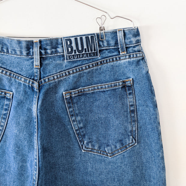 Vintage B.U.M. Equipment Blue Jeans. Solid Light-Medium Blue Wash. Women’s 18. Close-up of Blue BUM Equipment Logo.