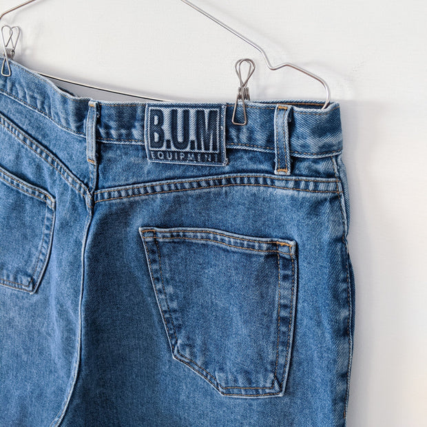 Vintage B.U.M. Equipment Blue Jeans. Solid Light-Medium Blue Wash. Women’s 18. Close-up of Blue BUM Equipment Logo.