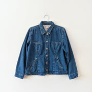 Cotton button-up denim jacket in Indigo Blue with collar. Four pockets, two welt pockets at the chest and two angled welt pockets lower down.