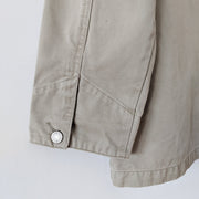 Close-up detail of cuff. It has a tapered sleeve with detailed stitching and a silver metal button. Cotton, field-style, barn jacket, chore coat in Sand Beige (like a greige, tan). Eddie Bauer Women's. Secondhand, from Fold and Fray.