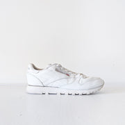 Side view of one White leather Reebok classic lace-up sneaker with white sole.