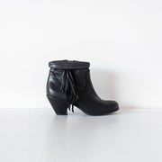 Outer side view of Black leather heeled ankle booties with almond toe. The top of the boot is shown roll down down over western-style fringe that is on the outer side of the boot. Sam Edelman Black Louie Boot 8M. Secondhand from Fold and Fray.