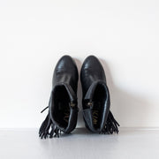 Top view of Black leather heeled ankle booties with almond toe. The top of the boot is shown roll down down over western-style fringe that hangs on the outer side of the boot. Sam Edelman Black Louie Boot 8M. Secondhand from Fold and Fray.