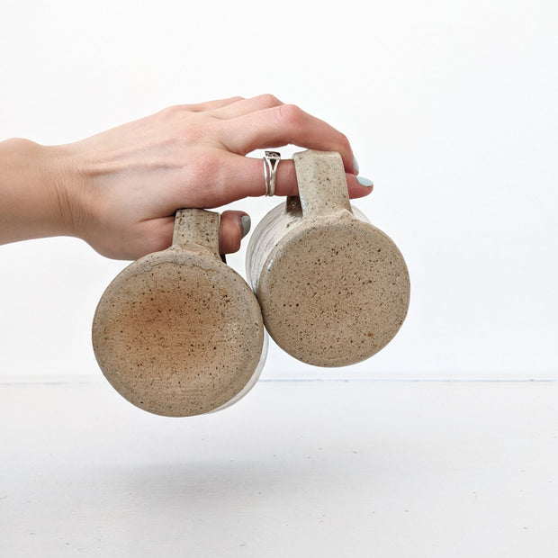 Bottoms of Two Tan/Brown Speckled Ceramic Mugs, Rough Texture. 