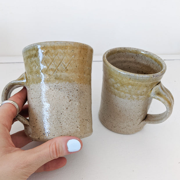 Close up of Tan/Brown Speckled Ceramic Mugs, Rough Texture with Glossy Glaze on Top Third. Shape Opens Wider at Mouth.