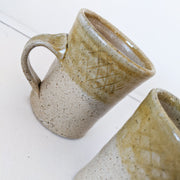 Close up of Tan/Brown Speckled Ceramic Mugs, Rough Texture with Glossy Glaze on Top Third. Shape Opens Wider at Mouth.