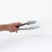 Hand Holding Stainless Steel Kitchen Tongs. Plastic-Free Used Home Goods in Guelph Ontario Canada from Fold and Fray.